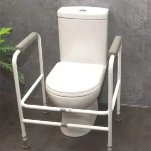 The Broadstairs Toilet Frame with Adjustable Height and Width, featuring metal arms, is placed around a white toilet set against a grey tiled wall on a dark floor.