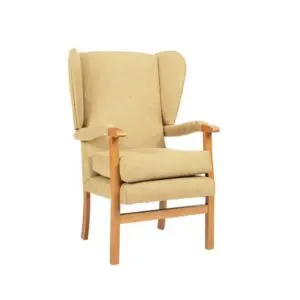 The Jubilee Fireside Chair is a beige upholstered high-backed armchair with wooden legs and armrests, winged sides, shown against a plain white background.