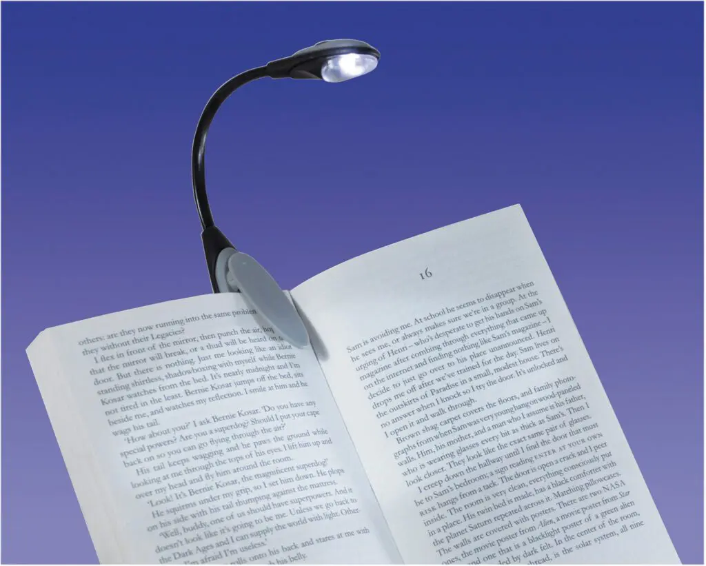 An LED Clip Light is attached to an open book, brightly illuminating its pages against a smooth gradient blue background.