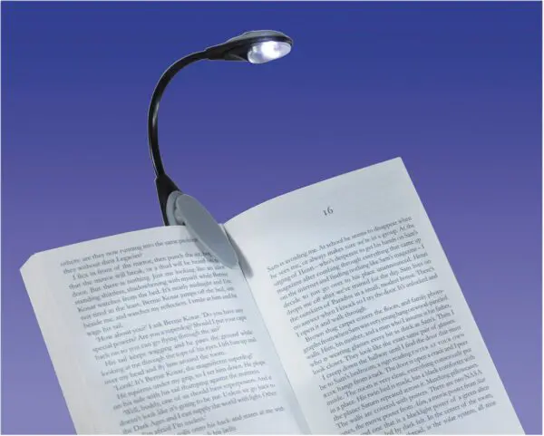 An LED Clip Light is attached to an open book, brightly illuminating its pages against a smooth gradient blue background.