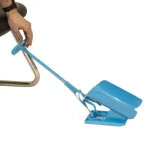 A person uses a Sock Aid Slider whilst seated on a chair.