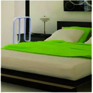 A modern bedroom with a double bed, lime green bedding, a bedside table, lamp, and the Solo Bed Transfer Aid—a white bed assist rail—beside the bed.