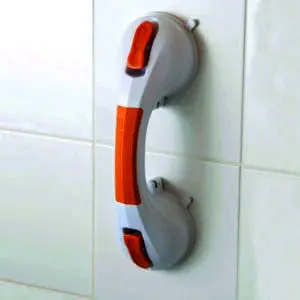 A white and orange suction cup grab rail attached to a tiled wall.