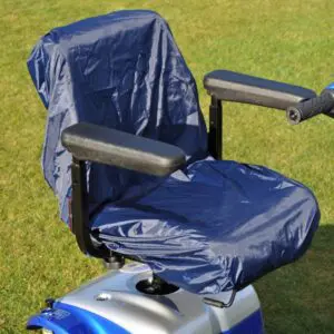 A blue mobility scooter with a blue protective cover on the seat, parked on green grass in daylight.