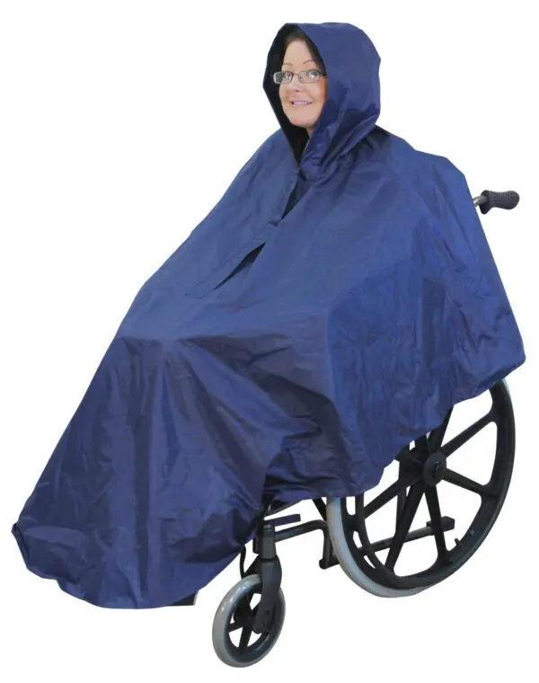 A person in a wheelchair wears the Wheelchair Poncho, a navy blue hooded rain poncho designed to cover both user and wheelchair.