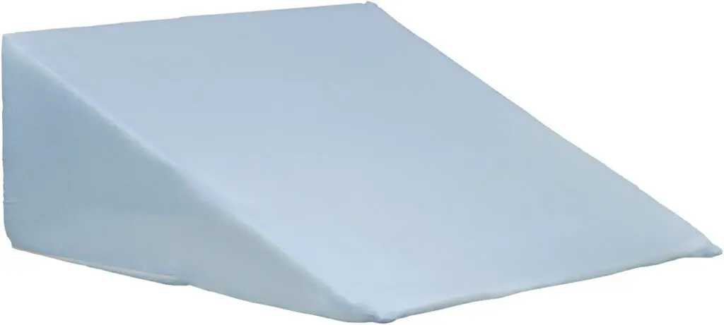 The Bed Wedge Cushion is a light blue, wedge-shaped pillow with a fabric cover, designed to provide support or elevation whilst lying down or sitting.