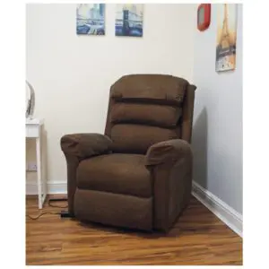 A brown recliner chair is placed in the corner of a room with wooden flooring, near a white desk and wall art.