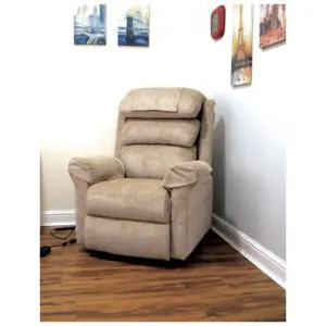 A beige recliner chair is positioned in the corner of a room with wooden flooring and framed art on the white walls.