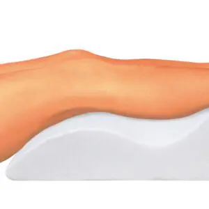 A person rests on their back with legs elevated on the Foam Leg Raiser, wearing black shorts and blue striped shoes.