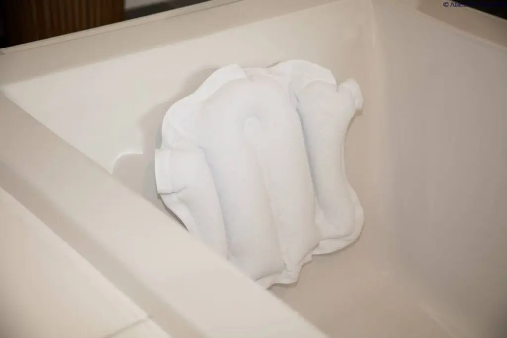 An Atlantis Bath Pillow is positioned against the backrest inside a white bath.
