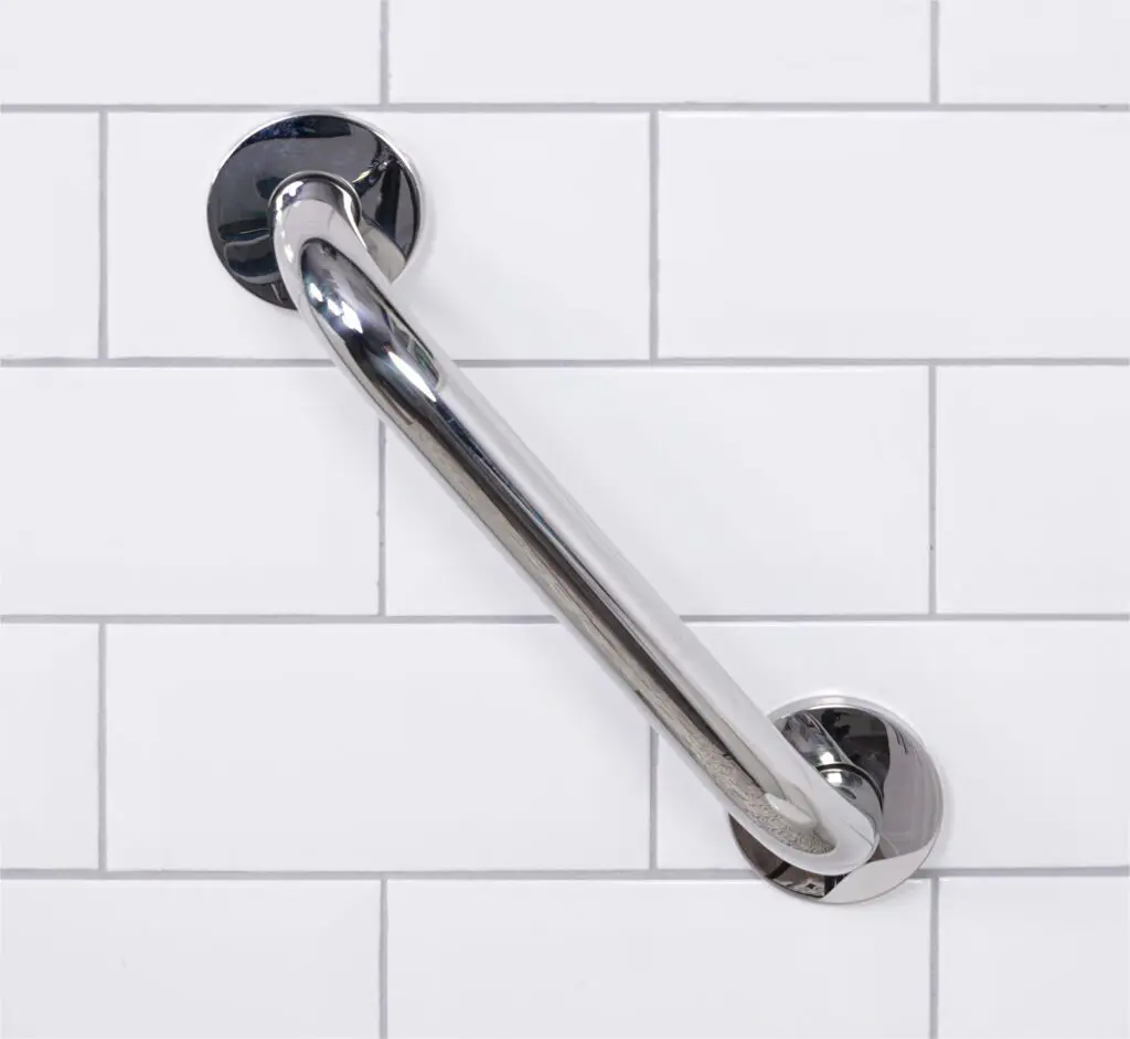 A stainless steel grab rail in a polished finish is mounted diagonally on a white tiled wall.
