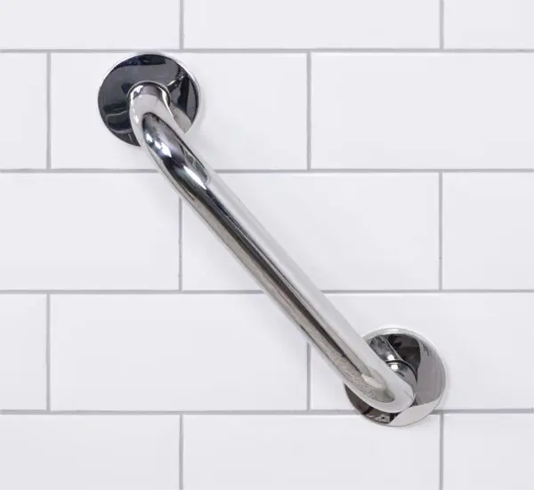 A stainless steel grab rail in a polished finish is mounted diagonally on a white tiled wall.