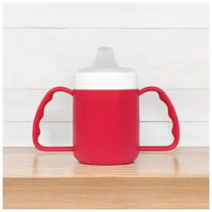 The Adult Drinking Cup (140ml) is a red beaker with two handles and a grey spout, shown on a wooden surface against a white background.