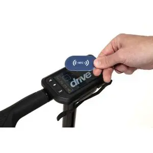A hand holds an NFC card above the display screen of an electric scooter, preparing to activate or unlock it.
