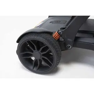 Close-up of a black rubber rear wheel with an orange suspension spring on a scooter against a white background.