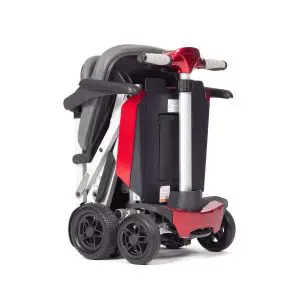 The Manual Fold+, a compact red and black mobility scooter, is displayed in its folded position, featuring four wheels and padded seat components.