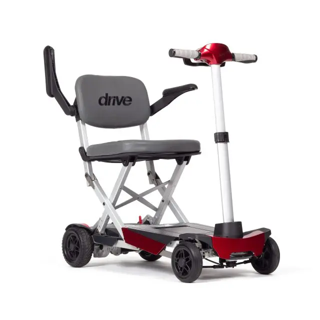 Manual Fold+ foldable mobility scooter featuring a grey seat, black armrests, four wheels, and red accents, displayed upright against a white background.