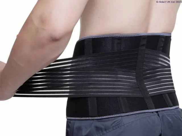 A person wearing and adjusting the Aero-Tech Neoprene Advanced Back Support - Universal around their lower back, pulling the straps for a snug fit.