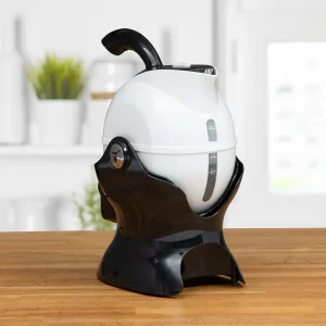 A white and black Uccello Kettle with measurement markings sits on a wooden worktop in a bright kitchen setting.