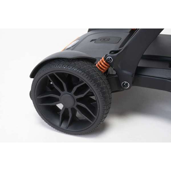 Close-up of a black rubber rear wheel with an orange suspension spring on a scooter against a white background.