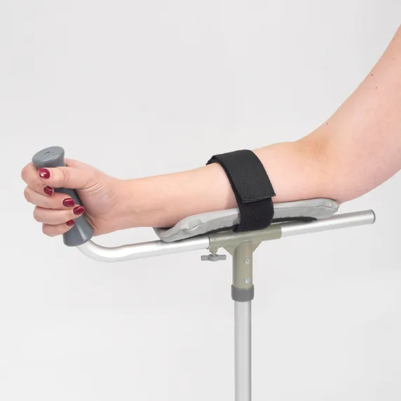 A person's arm rests on a Forearm Platform/Trough Crutch, with a black strap securing their forearm and their hand gripping the handle.