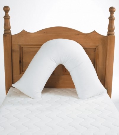 Harley ‘V’ Pillow in white, positioned upright on a mattress with a wooden headboard.