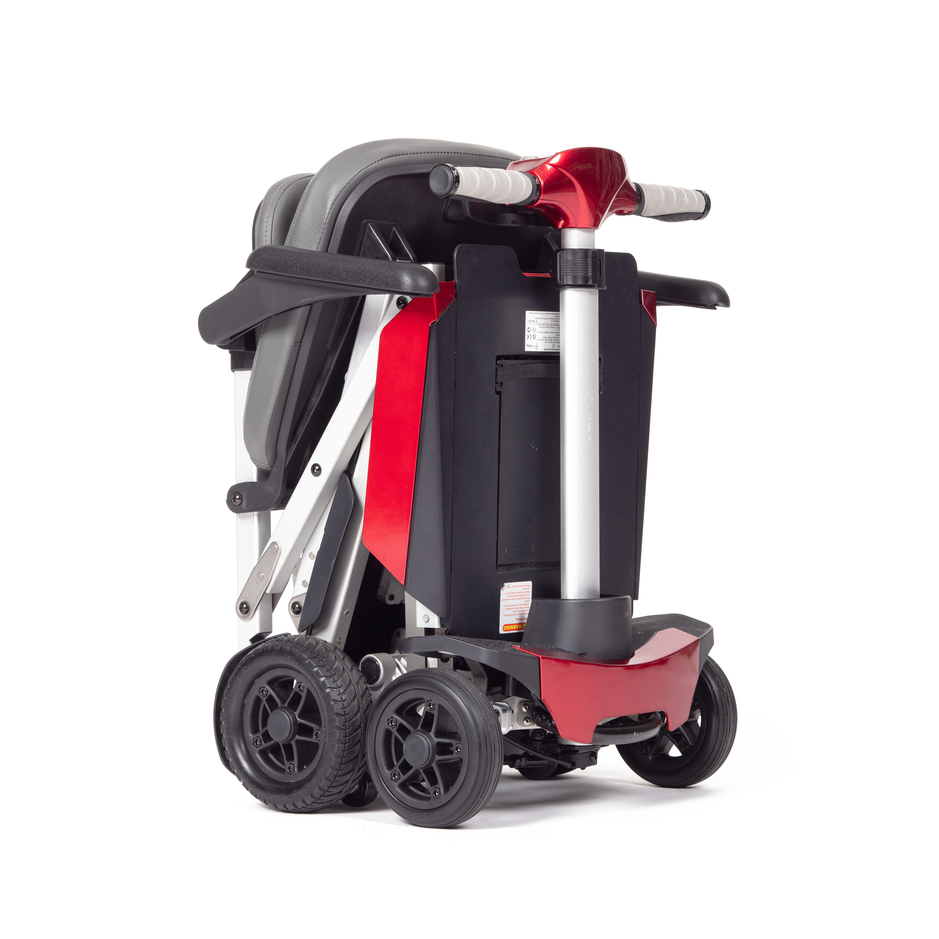 The Manual Fold+, a compact red and black mobility scooter, is displayed in its folded position, featuring four wheels and padded seat components.
