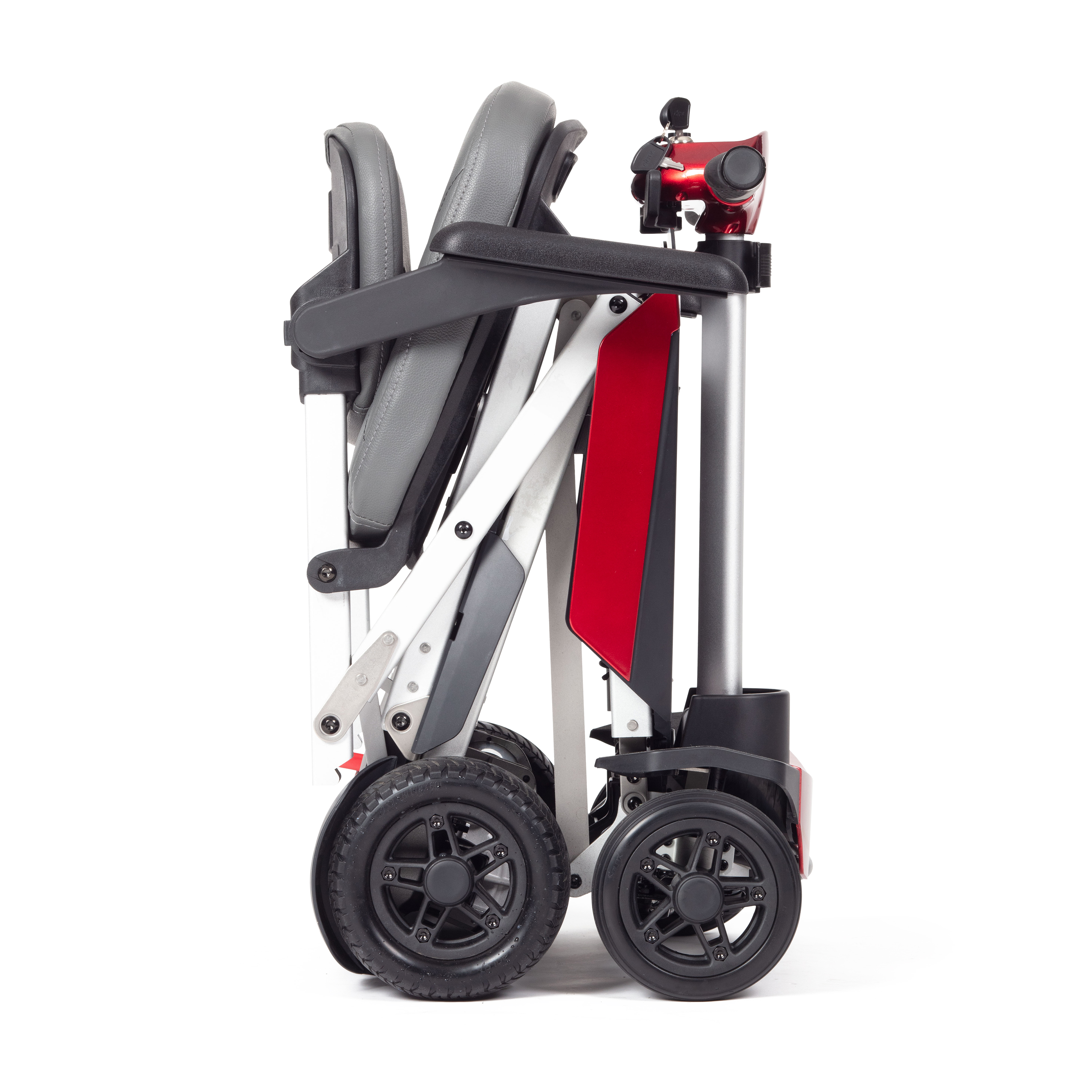 The Manual Fold+ is a compact, foldable mobility scooter featuring a grey seat and red frame, displayed here fully folded for convenient transport or storage.