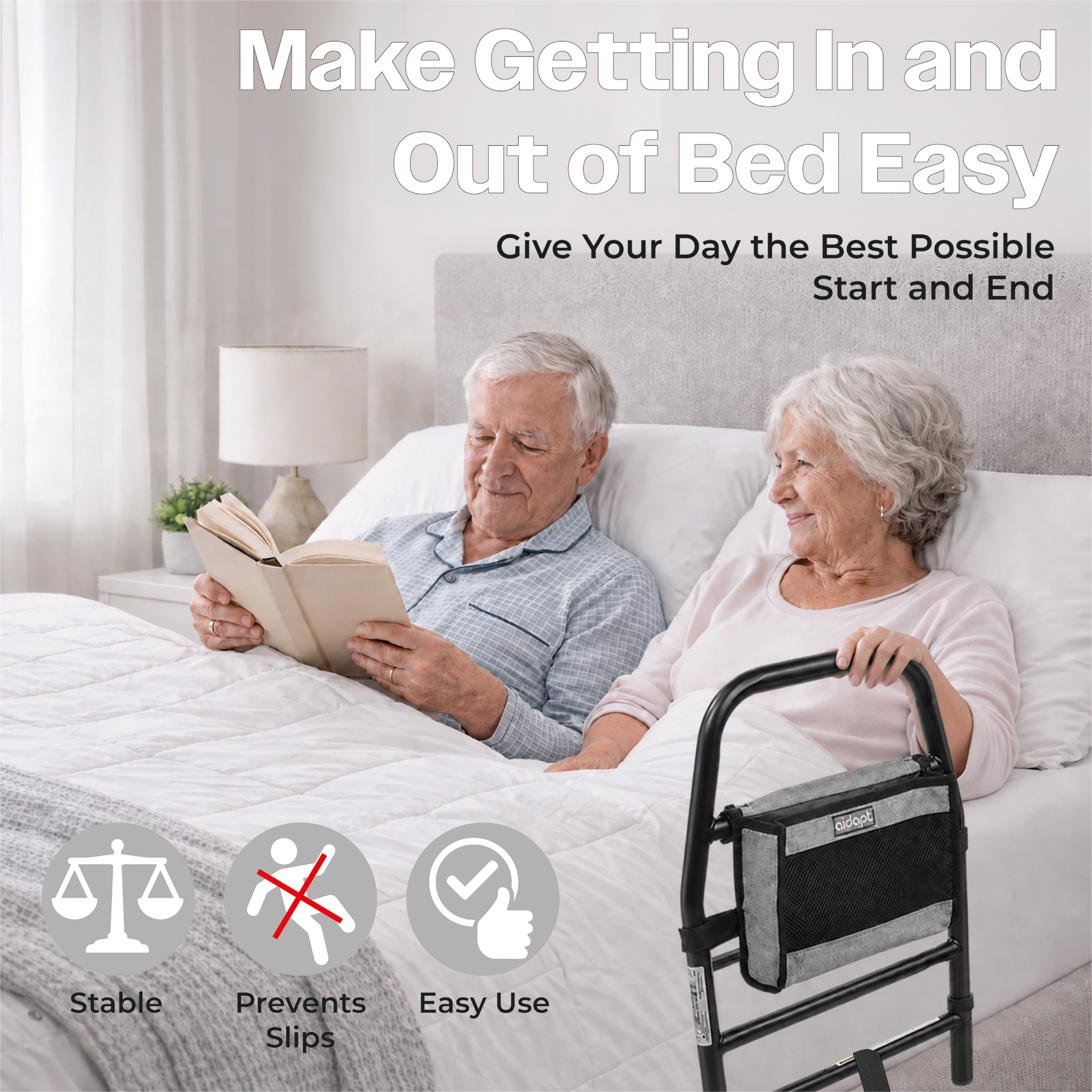 An elderly couple sits in bed reading, with a black Solo Bed Transfer Aid, Black featuring a storage pouch positioned at the bedside; includes text icons for stability, slip prevention, and easy use.